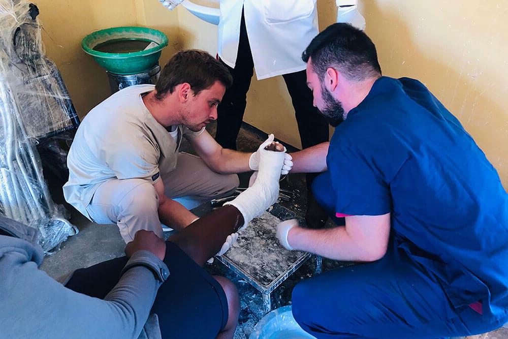 Physical therapy students examine Haitian patient's leg