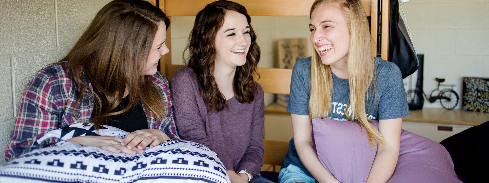 三个女学生坐在宿舍的双层床上